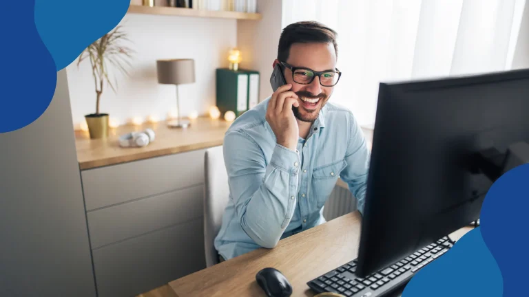 Planowane zmiany w pracy zdalnej – mężczyzna rozmawia przez telefon przy komputerze w domowym biurze