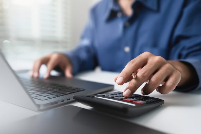 Close up businessman hand using calculator to budgeting and tax calculation monthly expenses. budget management and accounting on table. Business finance accounting banking concept
