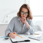 Bezpłatne webinary księgowe dla sektora publicznego – kobieta analizuje dokument na podkładce przy laptopie