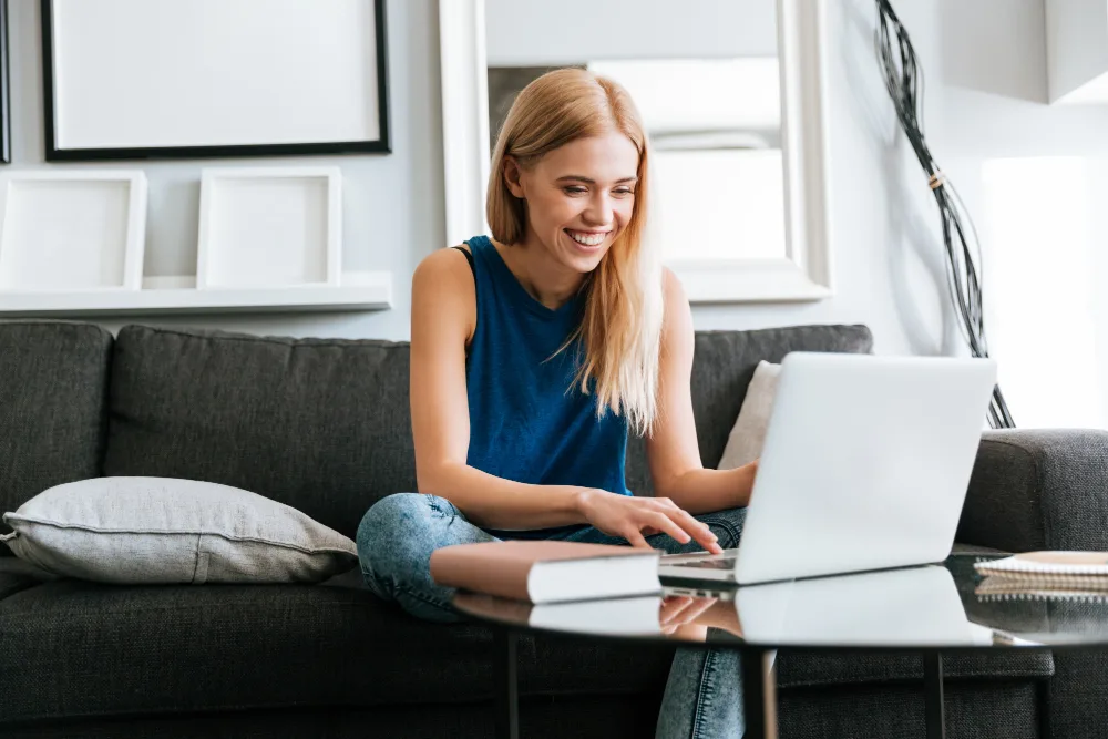 Uśmiechnięta kobieta ucząca się języka angielskiego online na laptopie w domu